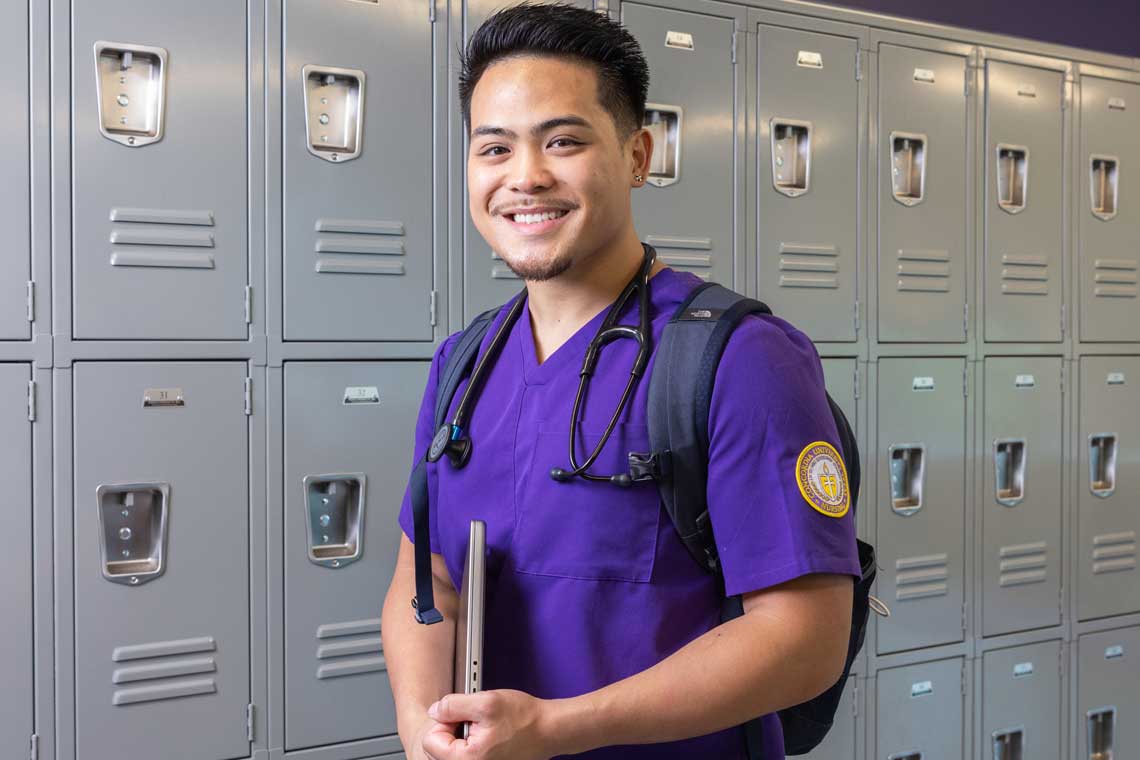 Nursing student smiling in front of lockers