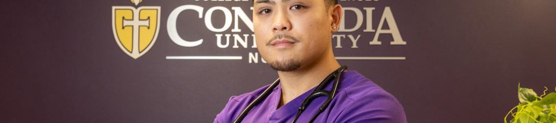 Male nursing student standing infront of sign