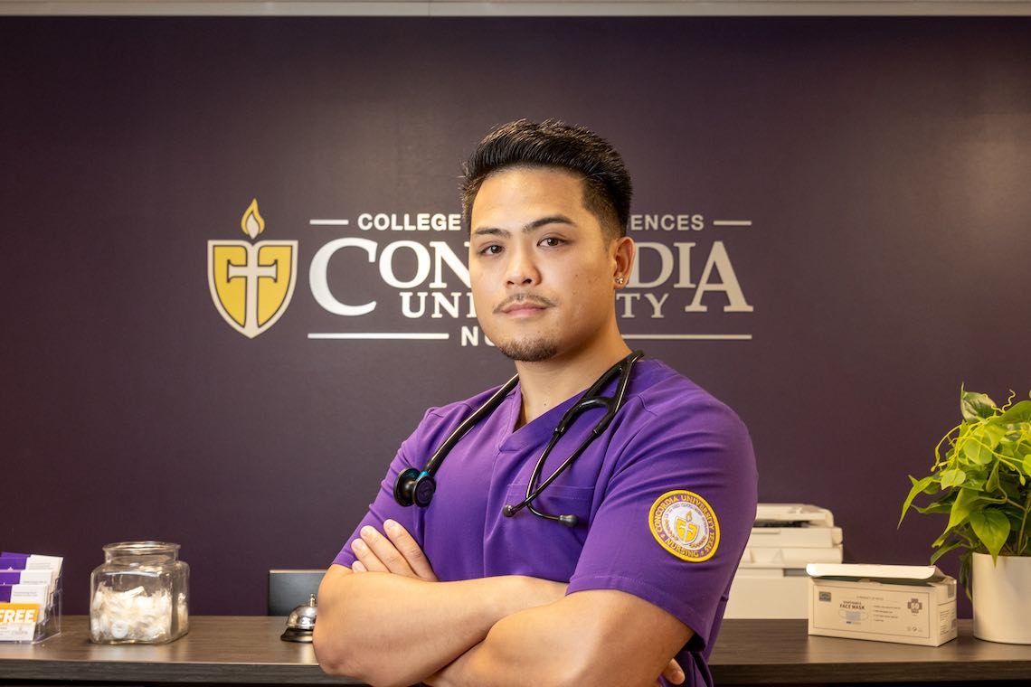 Male nursing student standing infront of sign